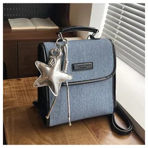 Detail of light blue denim backpack with black leather trim and silver star pendant