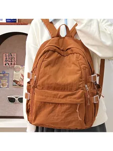 Detail view of large caramel nylon backpack with multi-pocket structure on a model