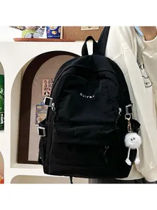 Side view of black nylon backpack with white embroidery and plush doll charm detail