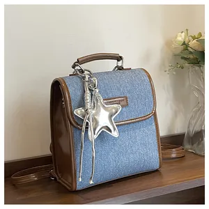 Detail of blue denim backpack with brown leather trim and silver star pendant accessory