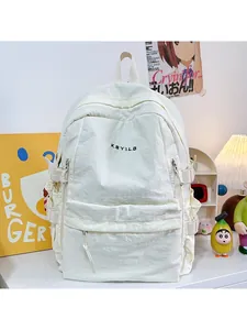 Detail of cream nylon backpack featuring black KBYILD embroidery and adjustable side buckles