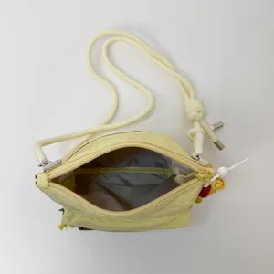 Light yellow nylon bucket crossbody bag with thick rope strap and spacious interior