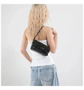 Close-up of black crocodile pattern shoulder bag with small gold logo and flap design