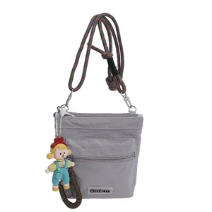 Gray nylon bucket bag with multiple zipper pockets and woven rope shoulder strap