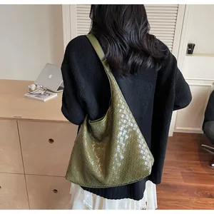 Dettaglio ravvicinato della trama intrecciata e del manico della borsa tote verde oliva