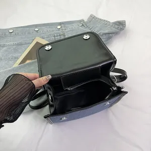 Blue denim and black faux leather crossbody bag with silver buckle and inner pocket
