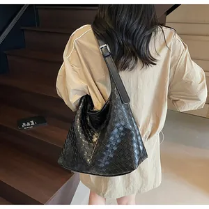 Dettaglio borsa hobo intrecciata nera con fibbia argentata su tracolla in pelle