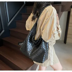 Modella che indossa una borsa tote nera intrecciata con trama in pelle di alta qualità