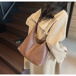 Dettaglio di una grande borsa tote in pelle intrecciata marrone indossata da modella