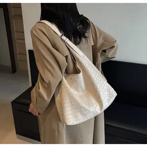 Dettaglio della borsa a tracolla intrecciata beige con ampia capacità e cinturino