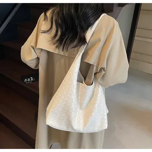 Vista posteriore di una modella con una grande borsa tote bianca in pelle intrecciata a spalla