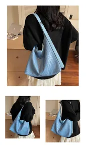 Dettaglio della borsa tote in pelle intrecciata azzurra portata a spalla in ambiente
