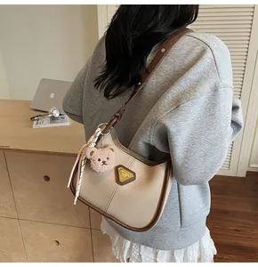 Détail du sac hobo avec logo en métal, breloque ours en peluche et décoration de foulard