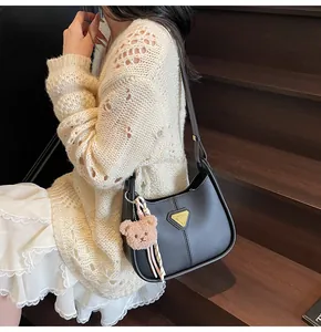Détail du sac à bandoulière en cuir noir mat avec dorure et pendentif ours mignon