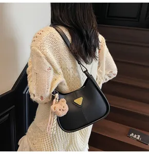 Détail du sac hobo en similicuir noir avec logo triangle doré et breloque ours