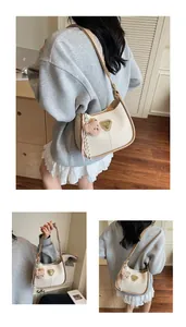 Détails du sac demi-lune blanc crème avec logo triangle et pendentif ours
