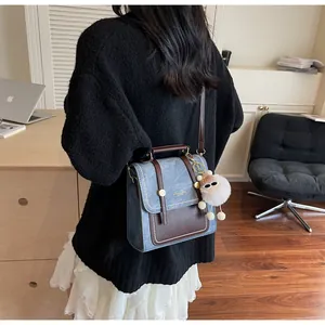 Rear view of a vintage denim and leather satchel bag with a cute bear charm accessory
