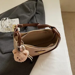 Sac fourre-tout chic beige et marron avec breloque ours sur fond de blazer gris