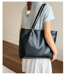 Détail d'un sac cabas vintage en cuir noir avec texture huilée et fines bretelles doubles