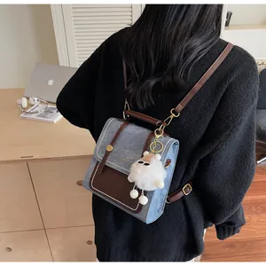 Detail of vintage denim backpack with brown leather trim and plush charm on a model