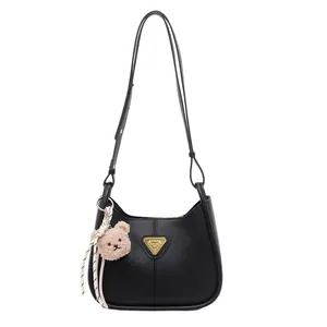 Sac à main demi-lune noir minimaliste avec détails dorés et charm ours en peluche