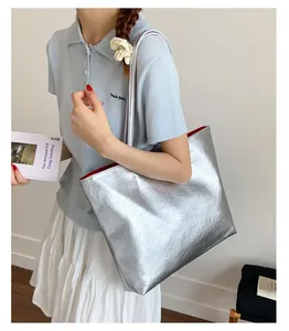 Détail du cabas argenté montrant la texture plissée et la doublure rouge vif