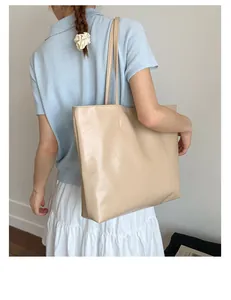 Détail d'un grand sac fourre-tout beige porté à l'épaule dans un décor intérieur épuré