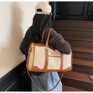 Close-up of canvas travel bag featuring brown leather trim and gold metal hardware