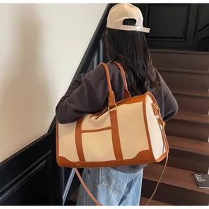 Canvas travel bag with leather trim carried by a model on wooden stairs, vintage style
