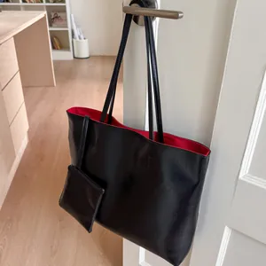 Gros plan du cabas en cuir noir avec doublure rouge et petite pochette suspendue