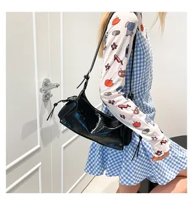 Mannequin portant un sac sous le bras en cuir noir brillant avec bandoulière réglable