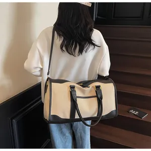 Large canvas travel bag with leather straps worn by model on stairs during a short trip