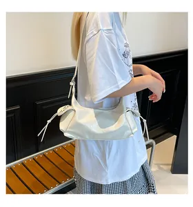 Détail d'un sac à bandoulière blanc crème en cuir brillant avec des cordons décoratifs