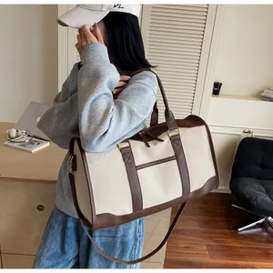 Detail of canvas travel bag featuring brown leather trim and adjustable shoulder strap