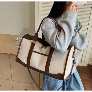 Lifestyle shot of model carrying a large canvas travel duffel bag with leather trim