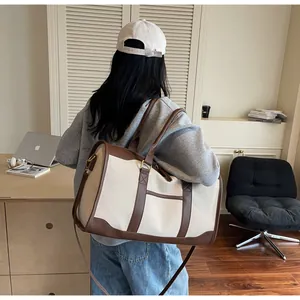 Detail of canvas travel bag with brown leather handles worn by a model in interior