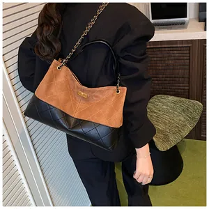 Détail du sac seau contrasté avec cuir noir matelassé et finition en daim marron