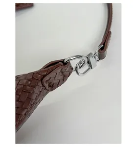 Close-up of brown woven leather texture and silver metal hook detail on shoulder bag