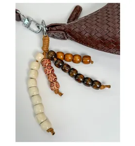 Detail view of brown woven leather bag with colorful beaded charms and silver metal ring