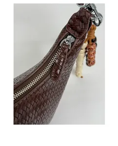 Detail of hand-woven vintage shoulder bag in dark coffee leather with silver zipper close-up