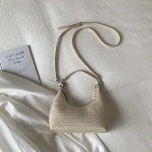 Detail of a beige woven hobo bag with adjustable strap on white fabric background