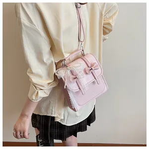Borsa a tracolla rosa con pizzo, catena di perle e fiocco indossata da una modella