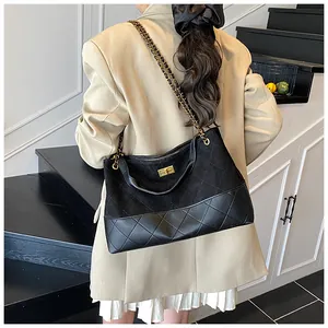 Détail du sac seau noir matelassé avec bandoulière chaîne dorée et boucle en métal vintage