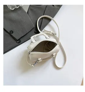 Detailed macro view of white lychee pattern leather handbag with silver zipper and strap
