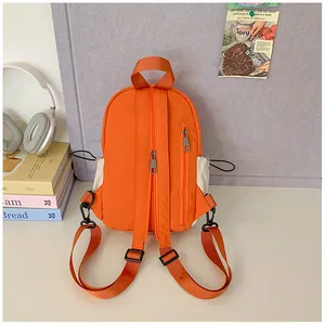 Rear view of orange nylon mini backpack with adjustable straps and zip pocket