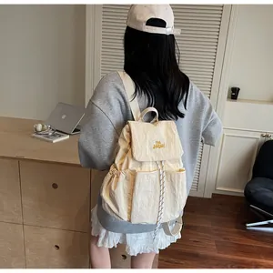 Dettaglio dello zaino in nylon crema con ricamo giallo e tasche laterali per uso quotidiano