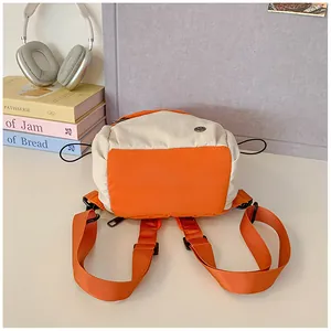 Detail of color-block mini backpack with cream and orange nylon panels and side drawstring