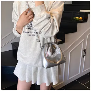 Detailansicht der silbernen Metallic-Tasche mit weißer Spitze und Plüsch-Hasenanhänger