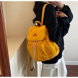 Dettaglio dello zaino in nylon giallo brillante con ricamo 'YOU BEAR!' e chiusura a cordoncino