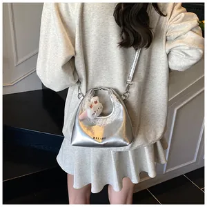Detail der silbernen Metallic-Tasche mit Spitzenbesatz und Plüschhasen-Anhänger
